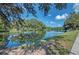 Another view of the lakefront property with lush green space and mature shade trees at 7302 Dunes Ct, Bradenton, FL 34202