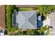 Aerial view of the home with a gray roof, screened-in pool, driveway, and lush surrounding greenery at 8804 Founders Cir, Palmetto, FL 34221