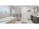 Well-lit bathroom with garden tub, shower, and dark wood vanity, featuring tile floors and large windows at 8804 Founders Cir, Palmetto, FL 34221