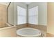 Elegant soaking tub with tile surround and natural light from corner windows at 8820 Heritage Sound Dr, Bradenton, FL 34212