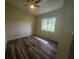 Bright bedroom featuring a ceiling fan, wood-look flooring, and a window offering a pleasant outdoor view at 9926 Gulfstream Blvd, Englewood, FL 34224