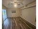 Spacious living room showcasing wood-look floors, natural light from a sliding glass door, and a ceiling fan at 9926 Gulfstream Blvd, Englewood, FL 34224