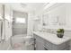 Well-lit bathroom with a shower-tub combo, a gray vanity, and tiled walls with decorative finishes at 1112 Montezuma Dr, Bradenton, FL 34209