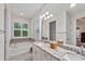 Bright bathroom with double sinks, granite counters, large mirror, and a soaking tub with decorative tile at 11434 Spring Gate Trl, Bradenton, FL 34211