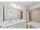 Bathroom featuring double sinks, white cabinets, a large mirror, and a shower-tub combo at 11434 Spring Gate Trl, Bradenton, FL 34211