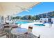 Community pool area featuring a pool, spa, seating, and a covered area with tables at 1300 N Portofino Dr # 103, Sarasota, FL 34242
