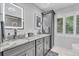 Modern bathroom with an illuminated mirror, double sink vanity with granite countertops, and storage tower at 1461 Marlin St, Nokomis, FL 34275