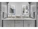 Bathroom featuring an undermount double sink vanity, granite counters, and two decorative, illuminated mirrors at 1461 Marlin St, Nokomis, FL 34275
