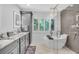 Modern bathroom with a sleek soaking tub, glass shower, and stylish gray vanity with ample counter space at 1461 Marlin St, Nokomis, FL 34275