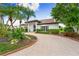 Beautiful home with mature trees and landscaping, a brick paved driveway and a black trim on the windows at 1484 Seafarer Dr, Osprey, FL 34229