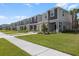 Community street view featuring modern townhouses, green lawns, sidewalks, and palm trees enhancing the curb appeal at 16652 Bergamo Pl, Bradenton, FL 34211