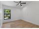 Minimalist bedroom with wood-look floors, modern ceiling fan and large picture window overlooking lush landscape at 1684 Pintail Way, Sarasota, FL 34231