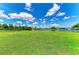 Lush green backyard that slopes to meet the waterfront, complemented by clear blue skies and scattered clouds at 208 147Th Ne St, Bradenton, FL 34212