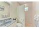 This bathroom features a stone countertop vanity, white toilet, neutral paint, and a tiled shower with a window at 208 147Th Ne St, Bradenton, FL 34212
