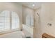 Bright bathroom featuring arch window with shutters, tiled shower with glass partition, and a corner soaking tub at 208 147Th Ne St, Bradenton, FL 34212