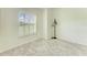 Well-lit bedroom featuring a window overlooking the yard, neutral carpeting, and a modern floor lamp at 208 147Th Ne St, Bradenton, FL 34212