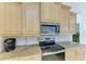 Modern kitchen featuring granite counters, stainless steel microwave and range, along with light wood cabinetry at 208 147Th Ne St, Bradenton, FL 34212
