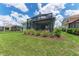 Well-manicured backyard with lush green grass, a covered patio, and beautifully maintained landscaping at 2565 Star Apple Way, Sarasota, FL 34240