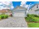 Lovely home with a well maintained lawn, a gray paver driveway, and a classic white two-car garage door at 2565 Star Apple Way, Sarasota, FL 34240
