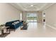 Bright living room with tile floors, a blue sofa, tray ceilings, a ceiling fan, and sliding glass doors to the backyard at 2565 Star Apple Way, Sarasota, FL 34240