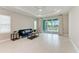 Bright living room with tile floors, a blue sofa, tray ceilings, a ceiling fan, and sliding glass doors to the backyard at 2565 Star Apple Way, Sarasota, FL 34240