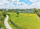 Expansive green community field with a sidewalk, single tree, landscaping, and a black fence border at 2565 Star Apple Way, Sarasota, FL 34240