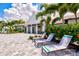 Lounge chairs in front of clubhouse overlooking the pool with tropical foliage and blue skies at 2565 Star Apple Way, Sarasota, FL 34240