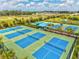 Aerial view of tennis courts with blue hard courts and trees in a beautiful community at 2565 Star Apple Way, Sarasota, FL 34240