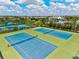 Aerial view of the blue community tennis courts with shelters and manicured landscaping in the background at 2565 Star Apple Way, Sarasota, FL 34240