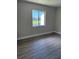 Bright bedroom featuring wood-look flooring and a window with a view of the community pond at 2636 Hidden Lake N Dr # G, Sarasota, FL 34237