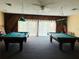 Bright game room featuring two pool tables with pendant lighting and natural light at 2636 Hidden Lake N Dr # G, Sarasota, FL 34237