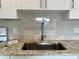 Close-up of the kitchen sink with stone countertops and a stylish backsplash at 2636 Hidden Lake N Dr # G, Sarasota, FL 34237