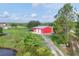 Aerial view of the property, highlighting the red metal garage building and a scenic landscape with blue skies at 3045 Logue Rd, Myakka City, FL 34251