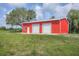 Exterior view of the bright red, two-door metal garage building with a well-manicured lawn at 3045 Logue Rd, Myakka City, FL 34251