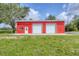 Front view of the red metal garage building, featuring two roll-up doors and a side entrance at 3045 Logue Rd, Myakka City, FL 34251