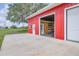 Garage of red metal building, with one open bay, one closed bay, and a large concrete parking pad at 3045 Logue Rd, Myakka City, FL 34251