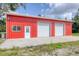 Close up of bright red outbuilding with two garage doors and a service door at 3045 Logue Rd, Myakka City, FL 34251