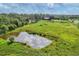 Picturesque pond reflecting the sky, surrounded by green fields and distant trees and barn at 3045 Logue Rd, Myakka City, FL 34251