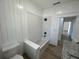 Bright bathroom with white plank walls, wood-look floors, and tub/shower with white subway tile surround at 3429 37Th N St, St Petersburg, FL 33713
