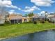 Spacious backyard featuring lush landscaping, a community lake view, and an enclosed patio at 3671 Summerwind Cir, Bradenton, FL 34209