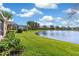 Expansive lawn area with lush landscaping, a lake view, and an enclosed patio at 3671 Summerwind Cir, Bradenton, FL 34209