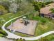 Community playground featuring modern play equipment, situated on a grassy area with mature trees and a walkway at 3671 Summerwind Cir, Bradenton, FL 34209