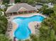 Aerial view of a community pool with a covered area and lounge chairs, surrounded by lush landscaping and palm trees at 3671 Summerwind Cir, Bradenton, FL 34209