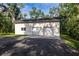 Large detached garage, featuring two garage doors and a side entry door, surrounded by mature trees at 3804 65Th E St, Bradenton, FL 34208