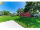 A view of a backyard featuring a storage shed, green grass, and a sunny sky at 444 Flamingo Dr, Apollo Beach, FL 33572