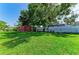 Large, grassy backyard with a storage shed and a white fence at 444 Flamingo Dr, Apollo Beach, FL 33572