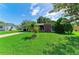 Well-manicured front yard with a young palm tree in front of a charming single-story home with mature trees at 444 Flamingo Dr, Apollo Beach, FL 33572