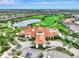 Expansive aerial view of a golf course with lush greenery, a scenic pond, and elegant clubhouse at 4540 Terrazza Ct, Bradenton, FL 34211