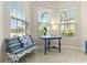 A sitting area is drenched in sunlight from three windows with a bench, small table and coastal decor at 4540 Terrazza Ct, Bradenton, FL 34211