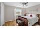 Cozy bedroom featuring wood floors, window with wooded view, ceiling fan, and decorative wall art at 4733 Spring Meadow Ln, Sarasota, FL 34233